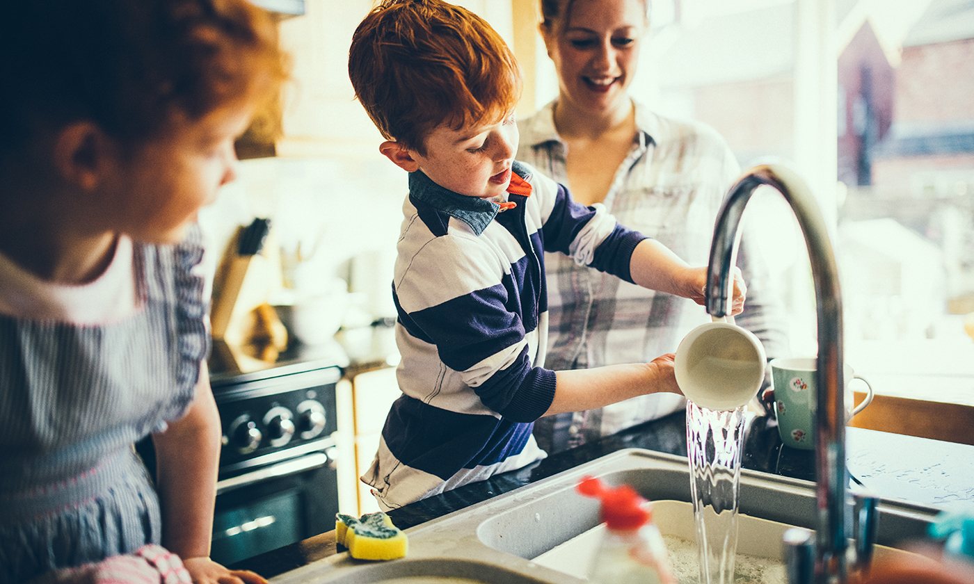 Little boy washing dishes