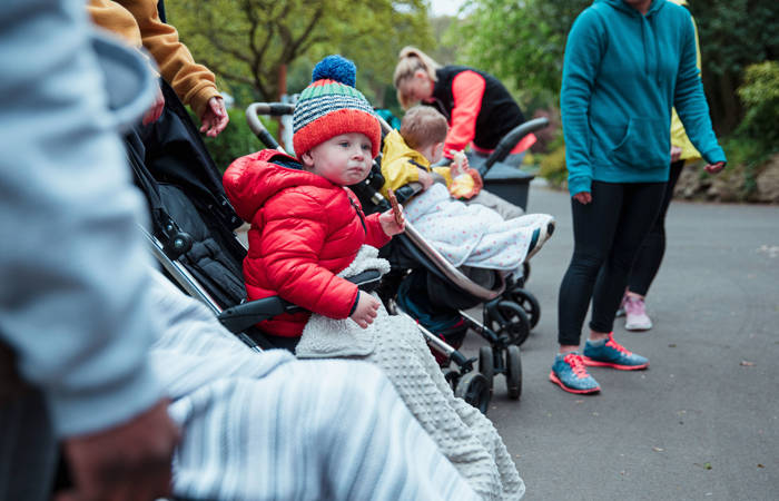 Agroup of mothers in the park with their children in baby strollers