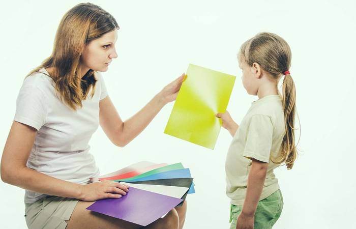 A child looking at coloured cards with an adult