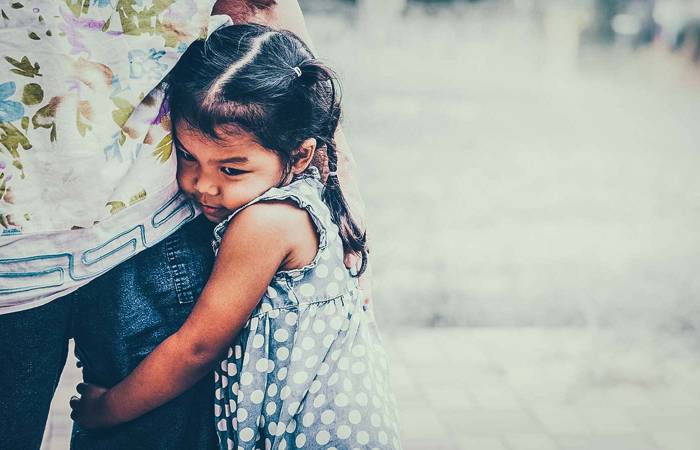 Little girl hugging parent's leg