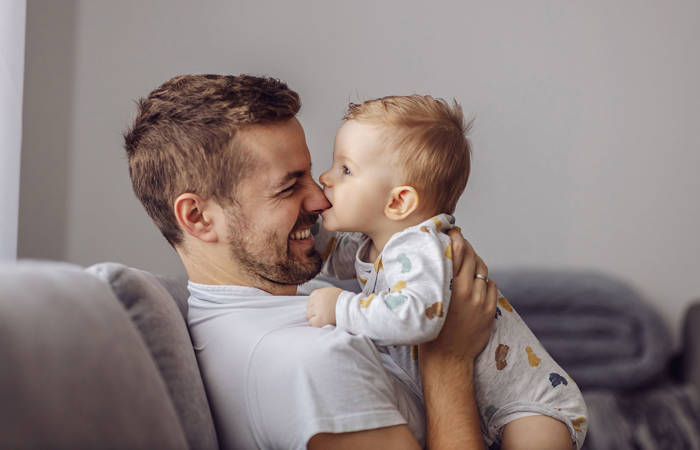 Boy playing with his father and biting his nose.