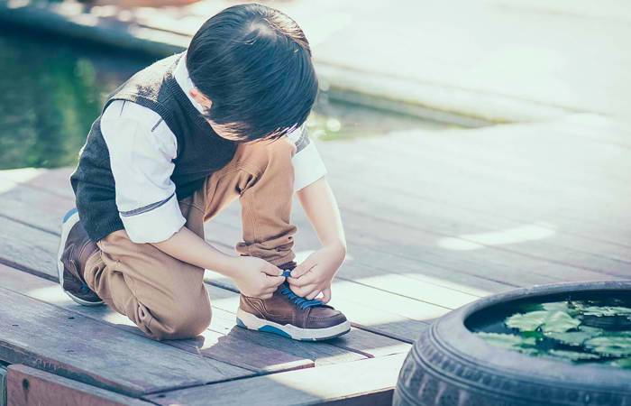 Boy trying to tie shoelace